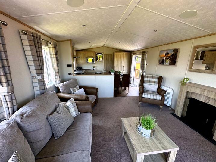 Open plan living area, including lounge, kitchen and dining area, leading out on to spacious decking and outdoor hot tub.
